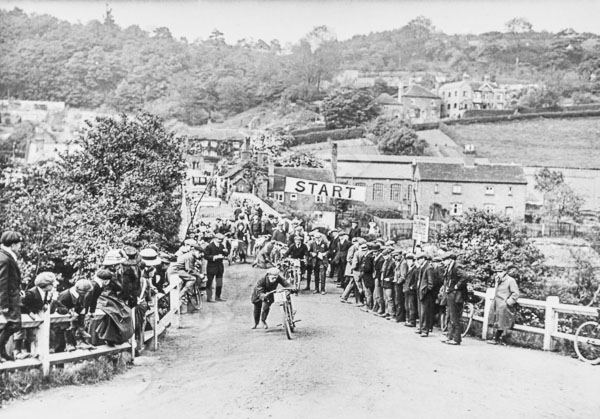 Crowds line the rails at the start of a hill climb at the bridge in May 1911, watching riders take off up Coalport Hill. The Sutton Coldfield Automobile Club ran this annual event across six classes, turning a working river crossing, for one day a year, into a grandstand for the new sport of motorcycling.