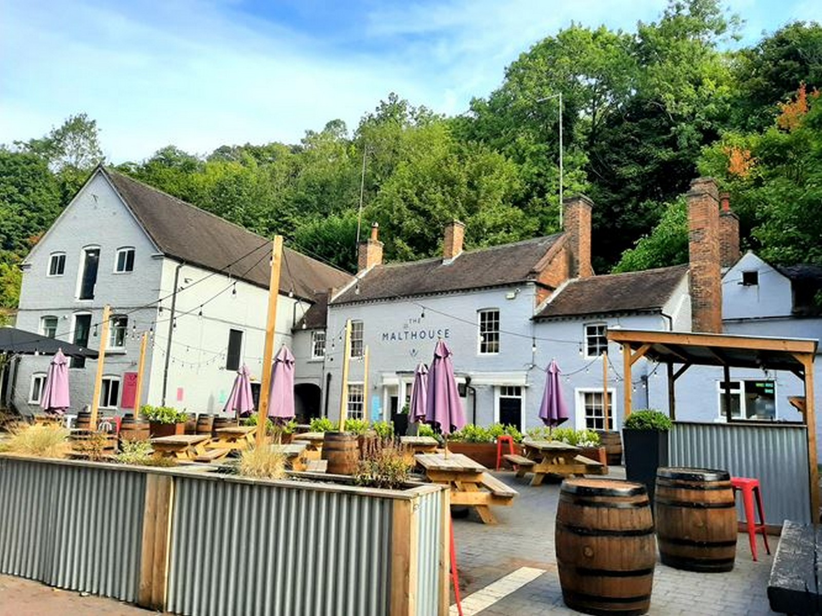 The courtyard today: benches, barrels and festoon lights where the dray horses and outings once assembled.