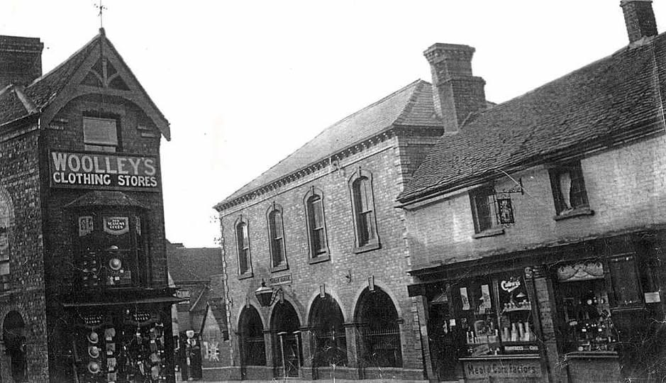 Woolley's Clothing Stores on the corner, the Old Police Station beyond and a meat contractor's shop on the right