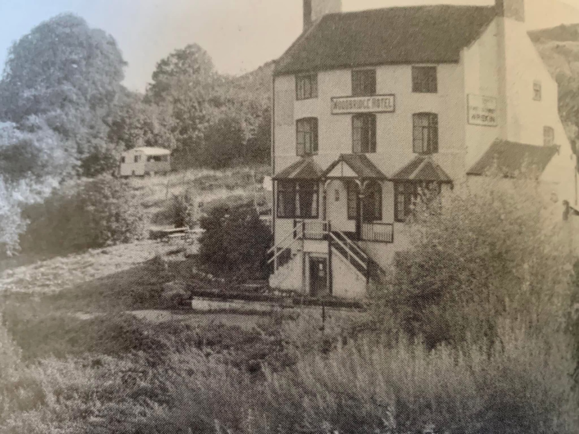 The Woodbridge Inn in earlier days, with the inn sign above the doorway and the river in the foreground.