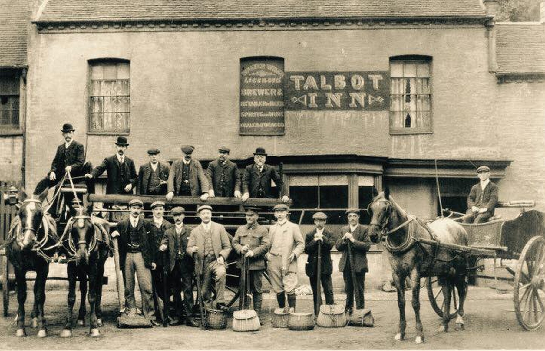 An outing assembles outside the Talbot Inn, the painted sign advertising a licensed retailer of beer, wines, spirits and tobacco.