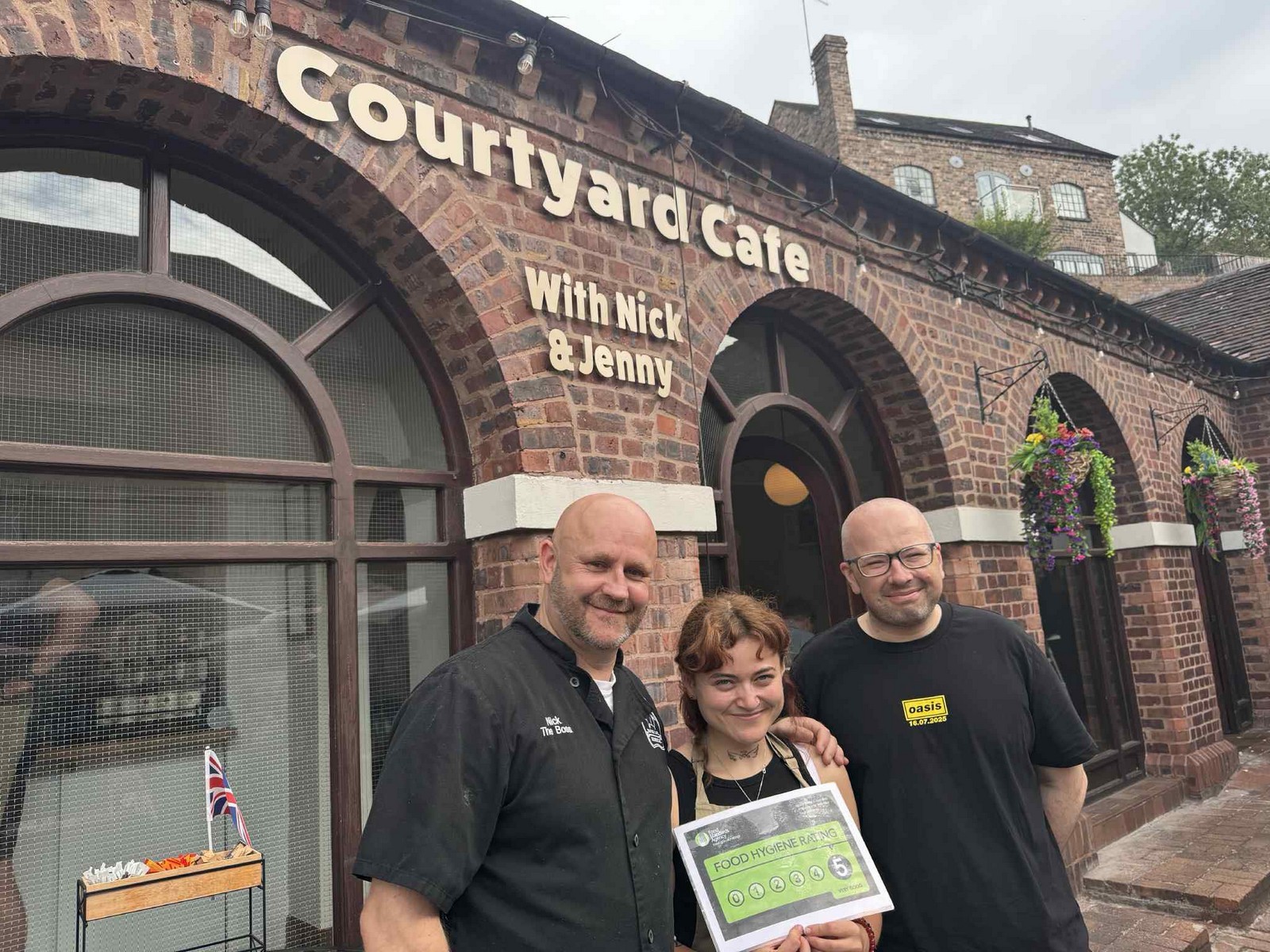 Courtyard Cafe under the brick arches, with Nick and Jenny behind the counter. The arches sheltering the tables were built for market traders, not for coffee — the building has changed its use without changing its shape. Present day.