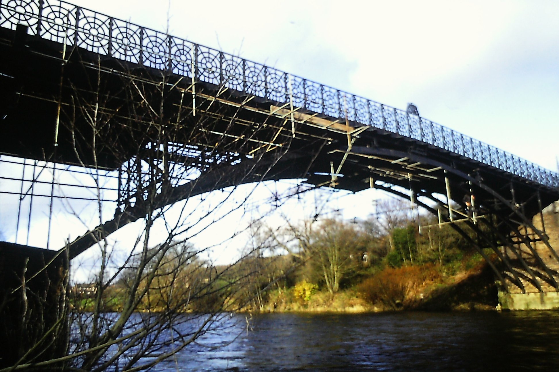 Looking along the underside of the deck towards the Coalport abutment, this modern photograph reveals the decorative circle-and-lozenge parapet pattern running the full length of the span. Cast at local foundries, that repeating motif was as much a display of engineering pride as it was structural bracing, and it still defines the bridge's silhouette today.