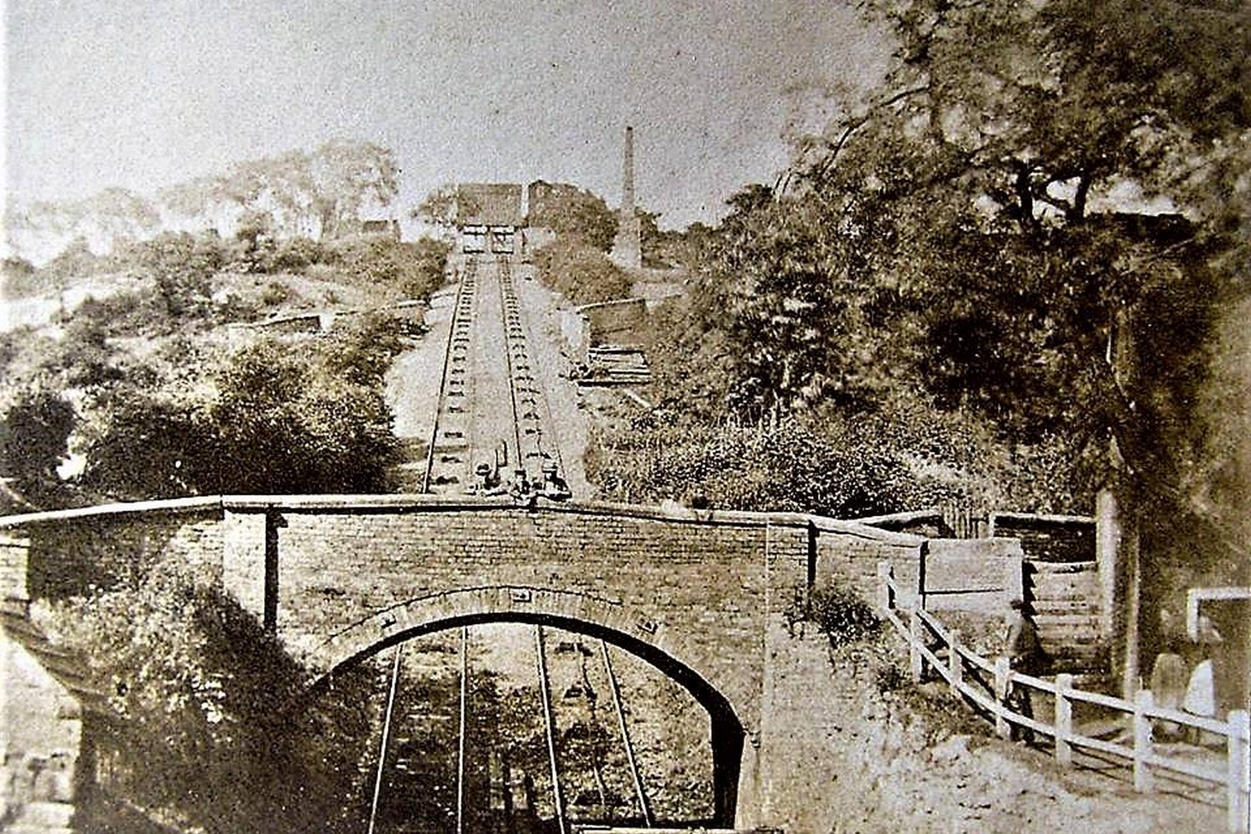 A sweeping panorama down the incline towards the brick bridge, the canal basin and the wharves beyond — the arch below carries Coalport High Street over the Coalport Canal at the foot of the Hay Inclined Plane. Exact date unknown, but the print's tone and composition place it firmly in the working decades of the incline's life.