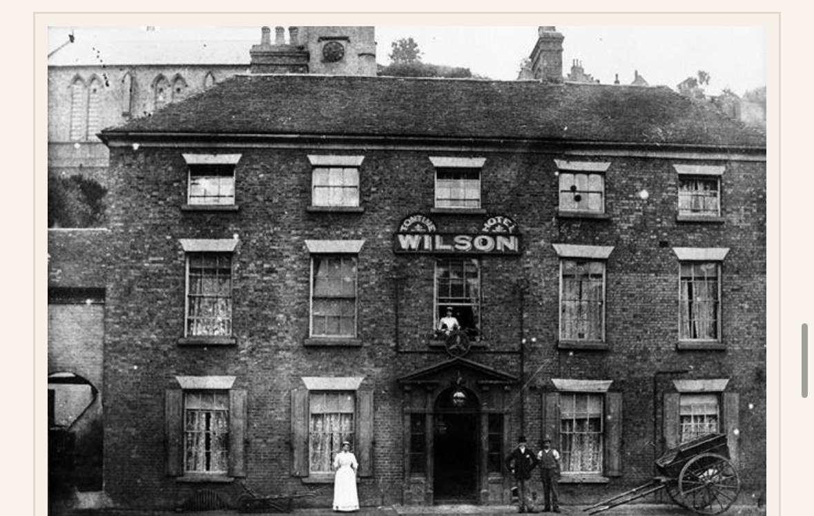 The Tontine Hotel under the Wilson name, with staff at the doorway and a delivery cart at the kerb.