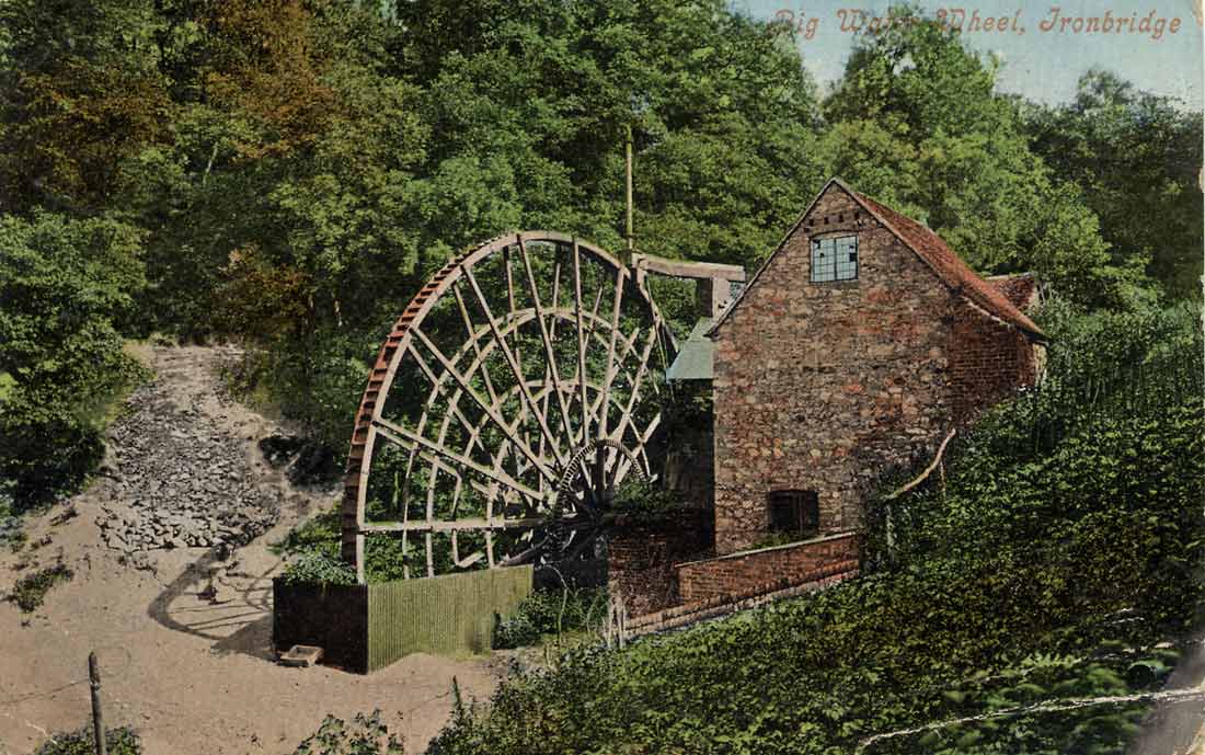 A coloured postcard titled "Big Water Wheel, Ironbridge", showing the wheel and the stone mill building among the trees.