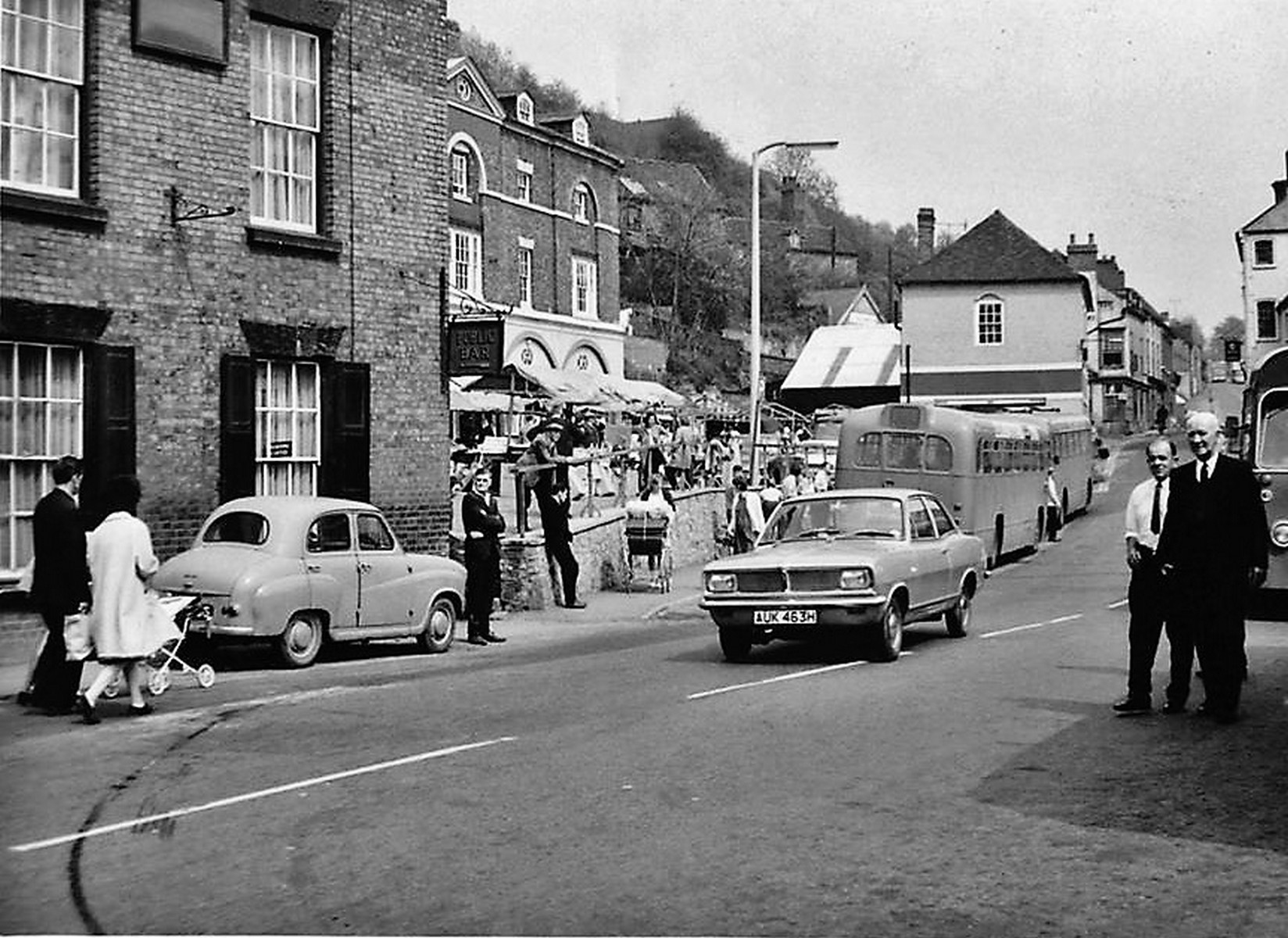 By the 1960s the stalls were squeezed into whatever space the parked cars left them, trestles set almost against bumpers. It is a small detail with a large meaning: the market was no longer the reason the Square existed, merely one of the things happening in it.