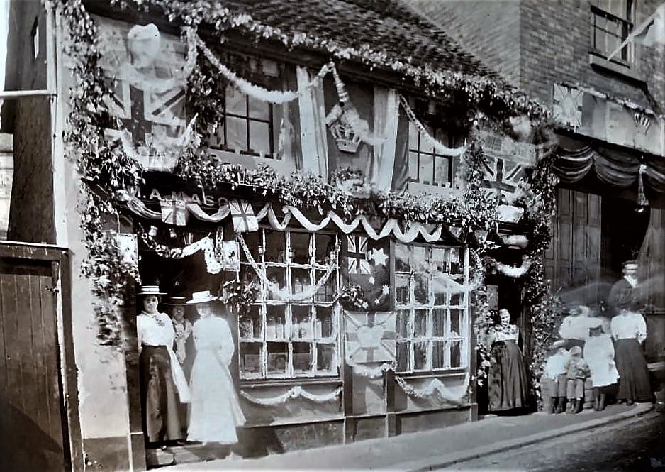 A shopfront dressed overall with flags, bunting and foliage for a celebration