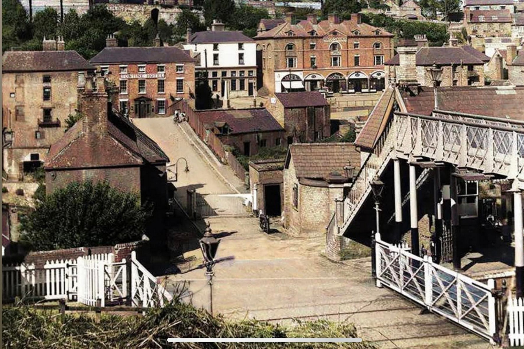 This undated, colourised photograph looks down on the crossing gates and up the bank towards the Tontine Hotel and the town beyond. The road from the station ran straight over this crossing and on to the Iron Bridge, tying rail and river crossing together in one continuous route through the Gorge.