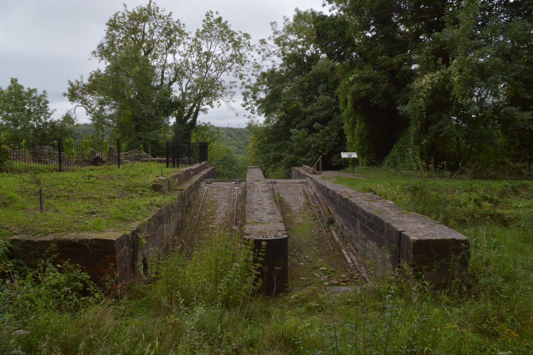 The drained, stone-lined basin chamber at the head of the incline sits dry and grassed over today. When it held water, this is where a tub boat floated onto its cradle, the rails running down into the basin itself, before the long descent to the canal below — a detail that explains the odd sunken rails still visible at the chamber's edge.