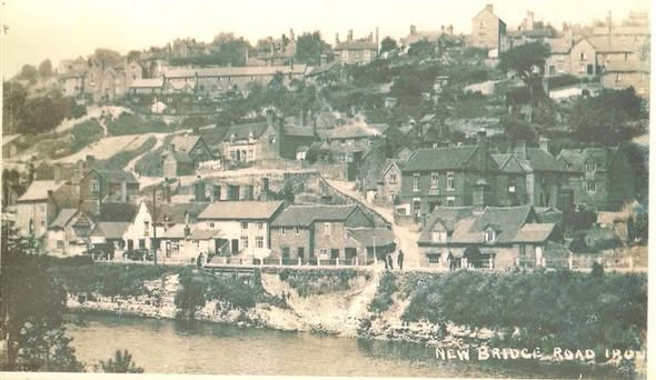 “New Bridge Road, Ironbridge” — the houses and shops climbing the bank above the river, from an old postcard view