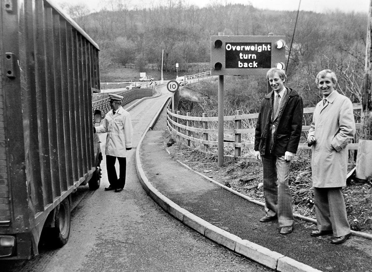 An articulated lorry sits halted in 1983, caught by a newly installed electronic sign reading “overweight — turn back”. Coalport became the first bridge in Britain fitted with this kind of electronic weighing pad, a genuinely pioneering piece of roadside technology deployed simply to protect a two-century-old iron span.