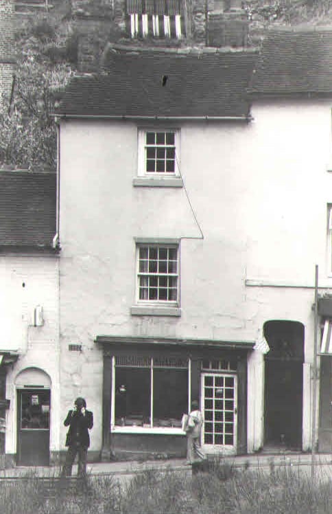 A rendered shopfront on the hill, its window still dressed