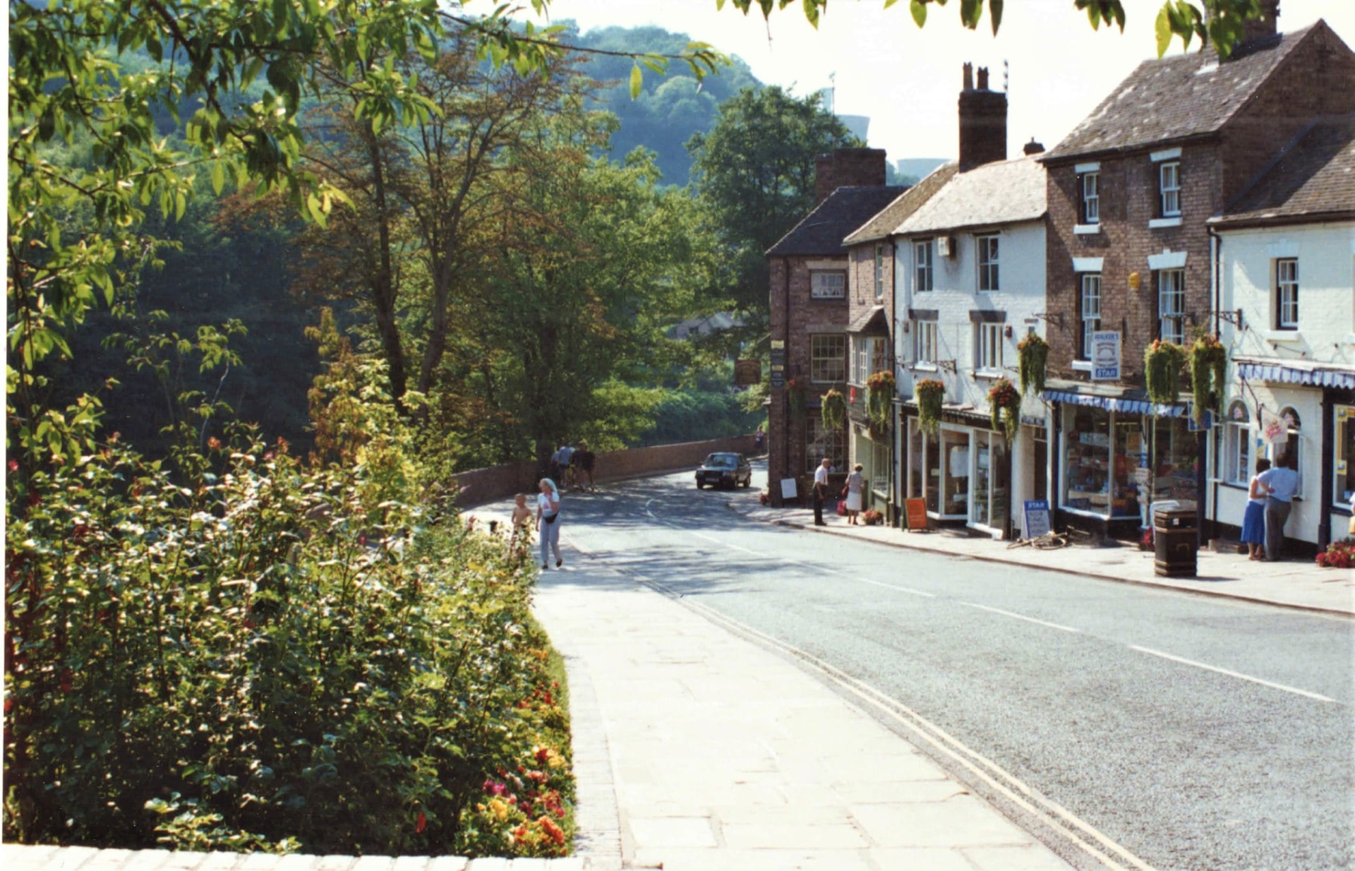 The hill opened out: shops on one side, planting and pavement on the other