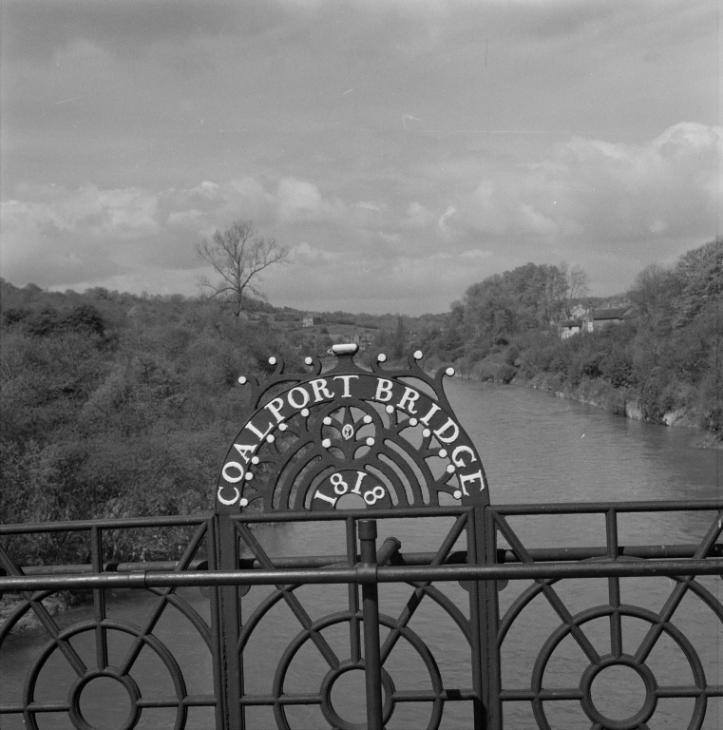 A close view of the cast-iron nameplate reading COALPORT BRIDGE 1818, set into the parapet where every crossing traveller would have passed it. This small plate is the bridge's own signature: it records the exact year John Onions rebuilt the earlier timber and masonry crossing in iron, the moment the structure we see today truly began.