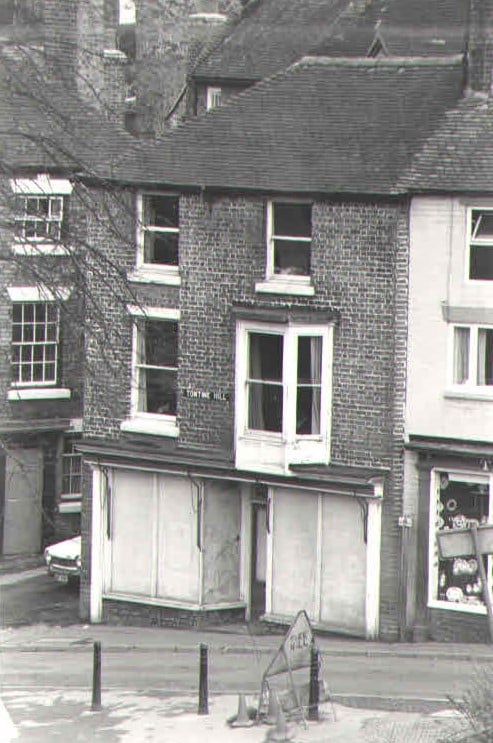 “Tontine Hill” lettered above a boarded-up shopfront